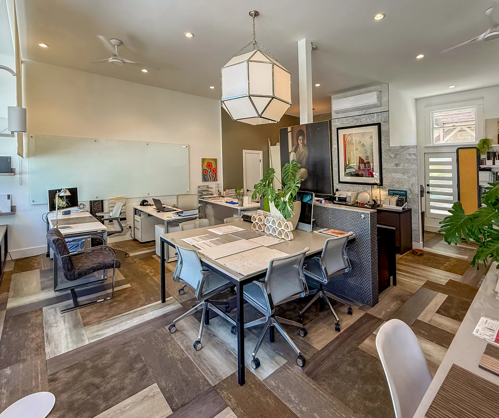 Inside the Keith Roberti Design studio in Bankers Hill, San Diego, with a central work table, drafting desks, a wall of material samples, and a geometric pendant light